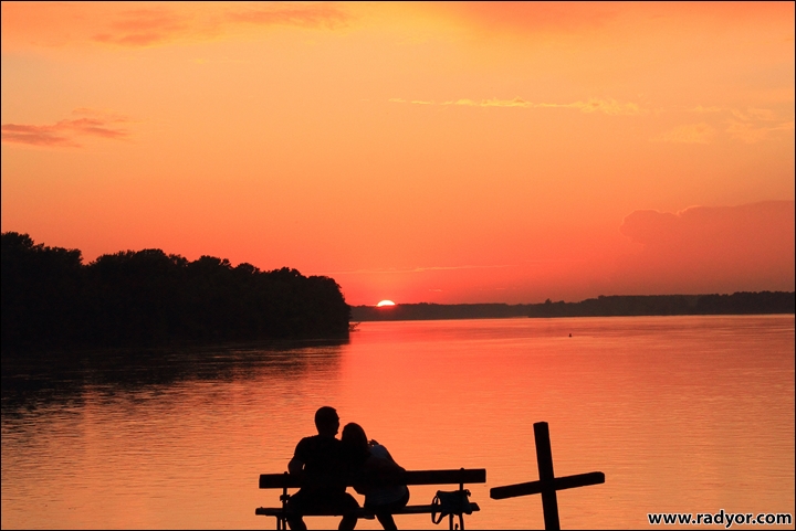 A couple is watching the sunset over Danube on the Serbian border with Croatia
